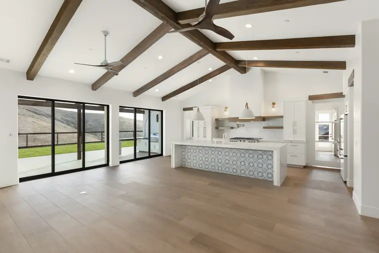 Great room with exposed beams, kitchen island, and glass doors to the view