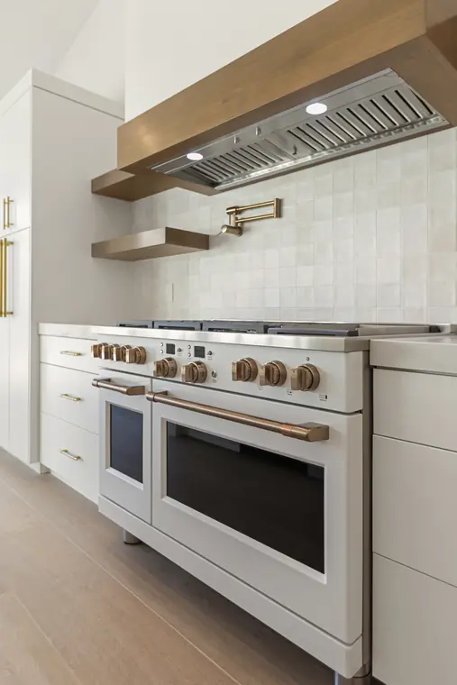 White range with copper hardware under a wood hood