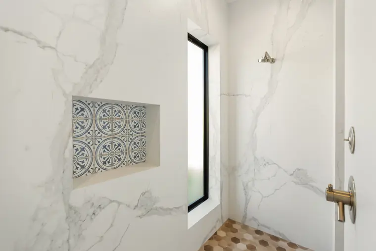 Marble-look shower with a patterned tile niche