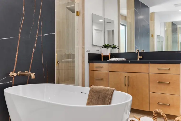 Freestanding tub beside a wood vanity with brass fixtures
