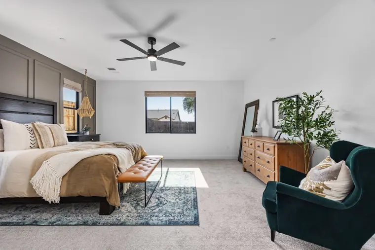 Primary bedroom with an upholstered bench and green accent chair
