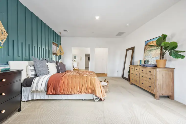 Primary bedroom with a teal accent wall and orange bedding