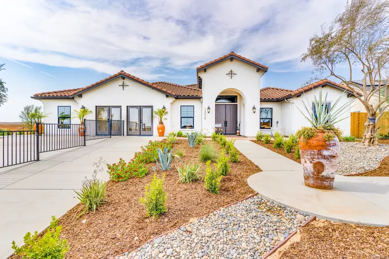 Spanish-style model home with a landscaped front walk