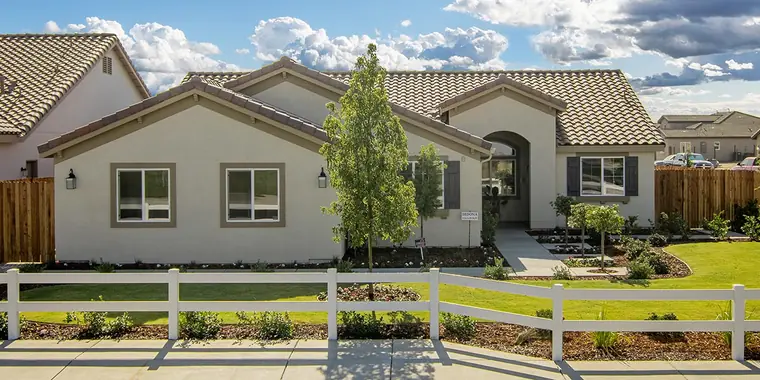 Single-story home with a white rail fence and landscaped yard