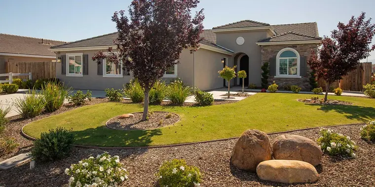 Model home with a lawn and landscaped boulders