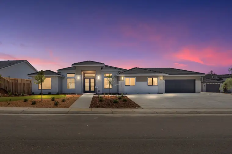 Contemporary single-story model home at dusk with lit windows