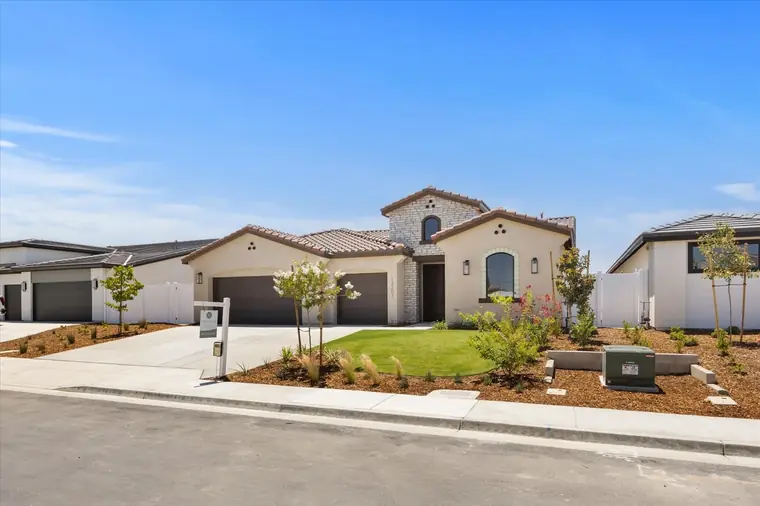 Spanish-style single-story home with a tile roof and landscaped front yard
