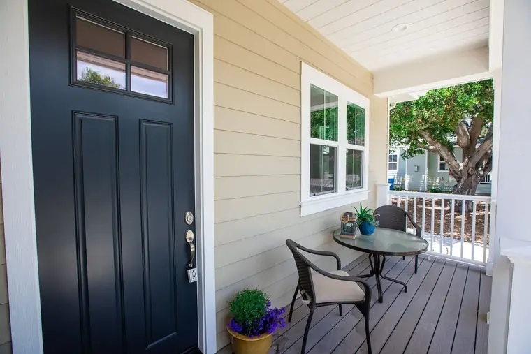 Black front door opening onto a covered porch