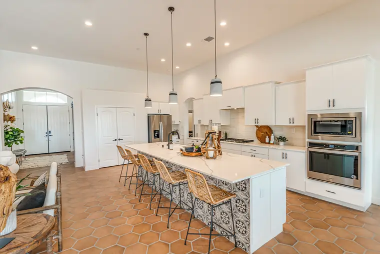Kitchen island with patterned tile and woven counter stools