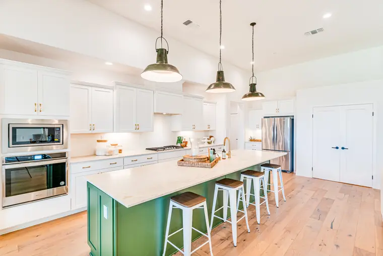 White kitchen with a green island and pendant lights