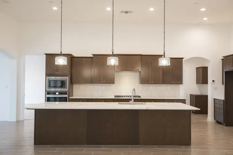 Kitchen with dark cabinetry, a long island, and pendant lights