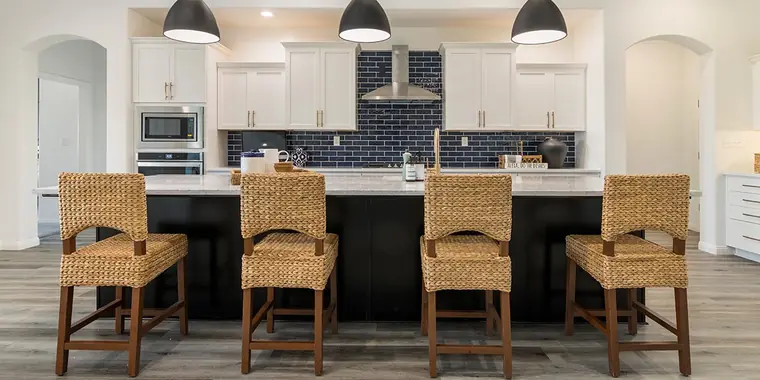 Kitchen island with woven stools and a blue tile backsplash
