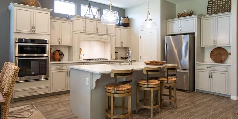 Kitchen with cream cabinetry, double wall ovens, and an island