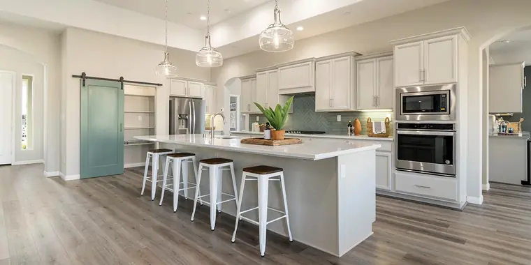 Long white kitchen island with metal stools and a sliding barn door