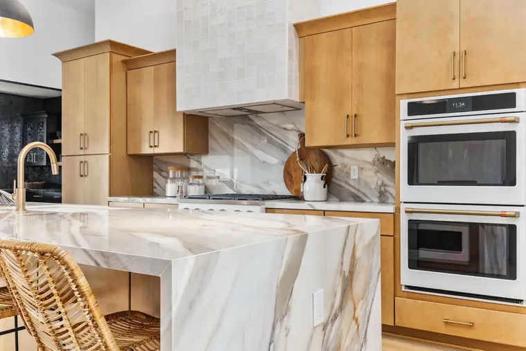Double wall ovens and wood cabinetry beside a marble island