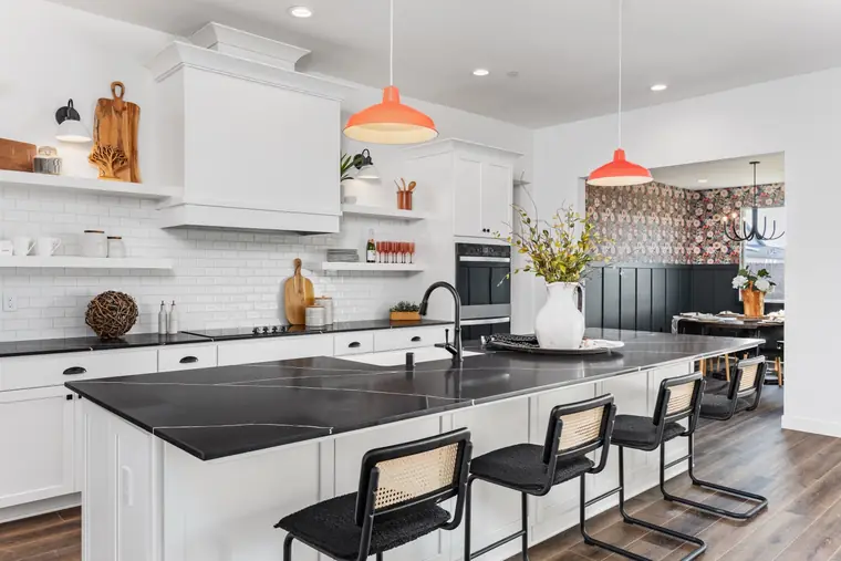 White kitchen with a black quartz island and red pendants