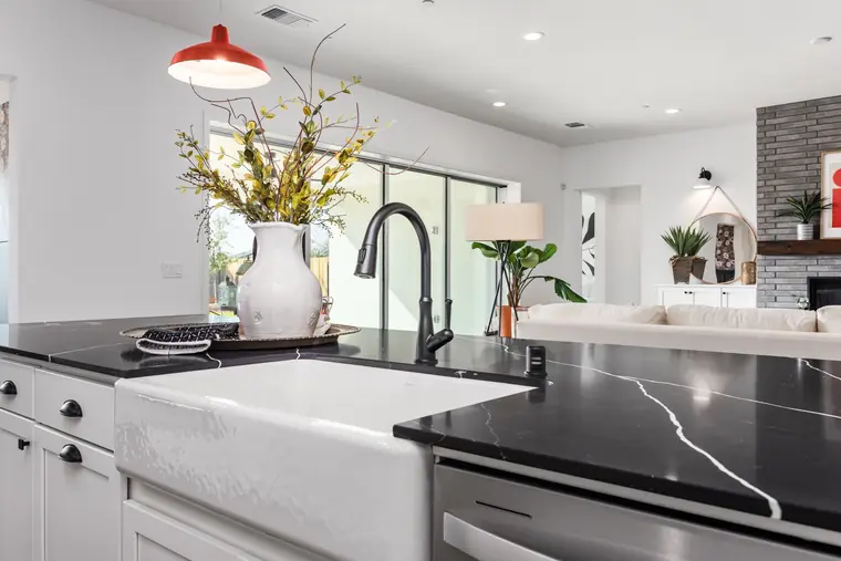 Farmhouse sink with a black faucet in a quartz island