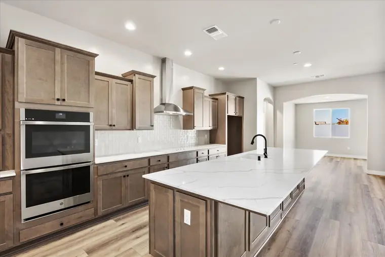Kitchen with a quartz island, double wall ovens, and gray-brown cabinetry