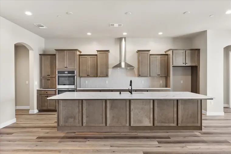 Long kitchen island with a stainless range hood and tile backsplash