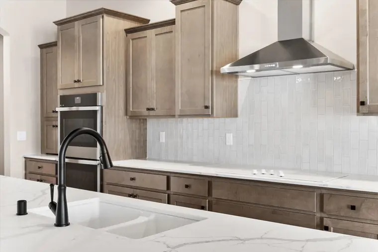 Black faucet and tile backsplash at a quartz kitchen counter