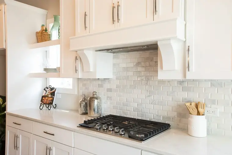 Gas cooktop with a tile backsplash and range hood