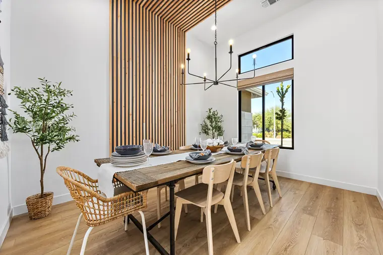 Dining room with a wood slat accent wall and modern chandelier