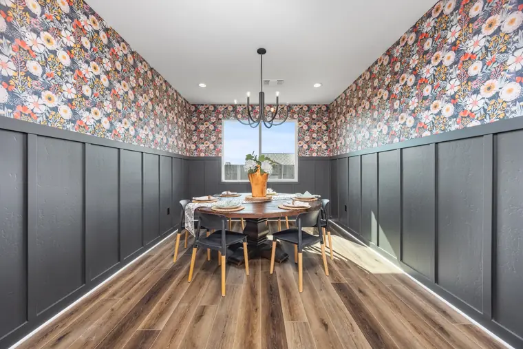 Dining room with floral wallpaper above dark wainscoting
