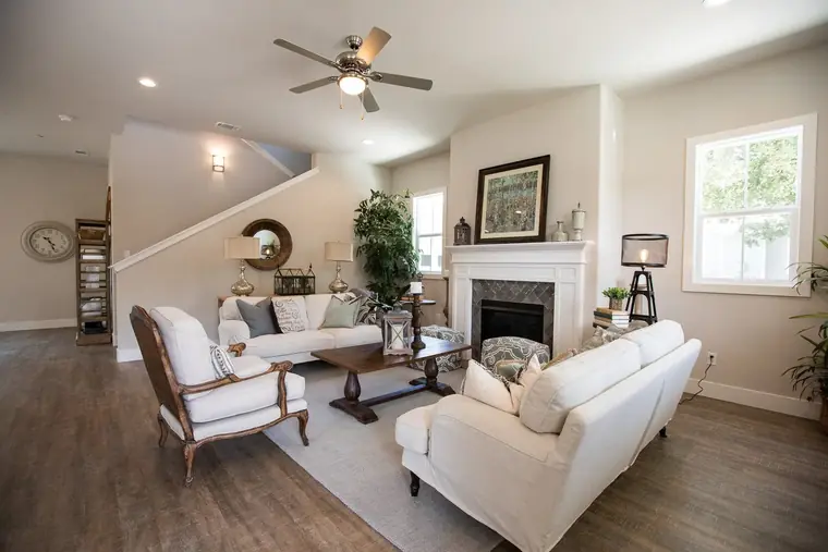 Family room with a fireplace, ceiling fan, and wood floors