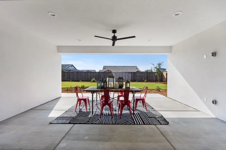 Covered patio with red dining chairs looking out to the lawn