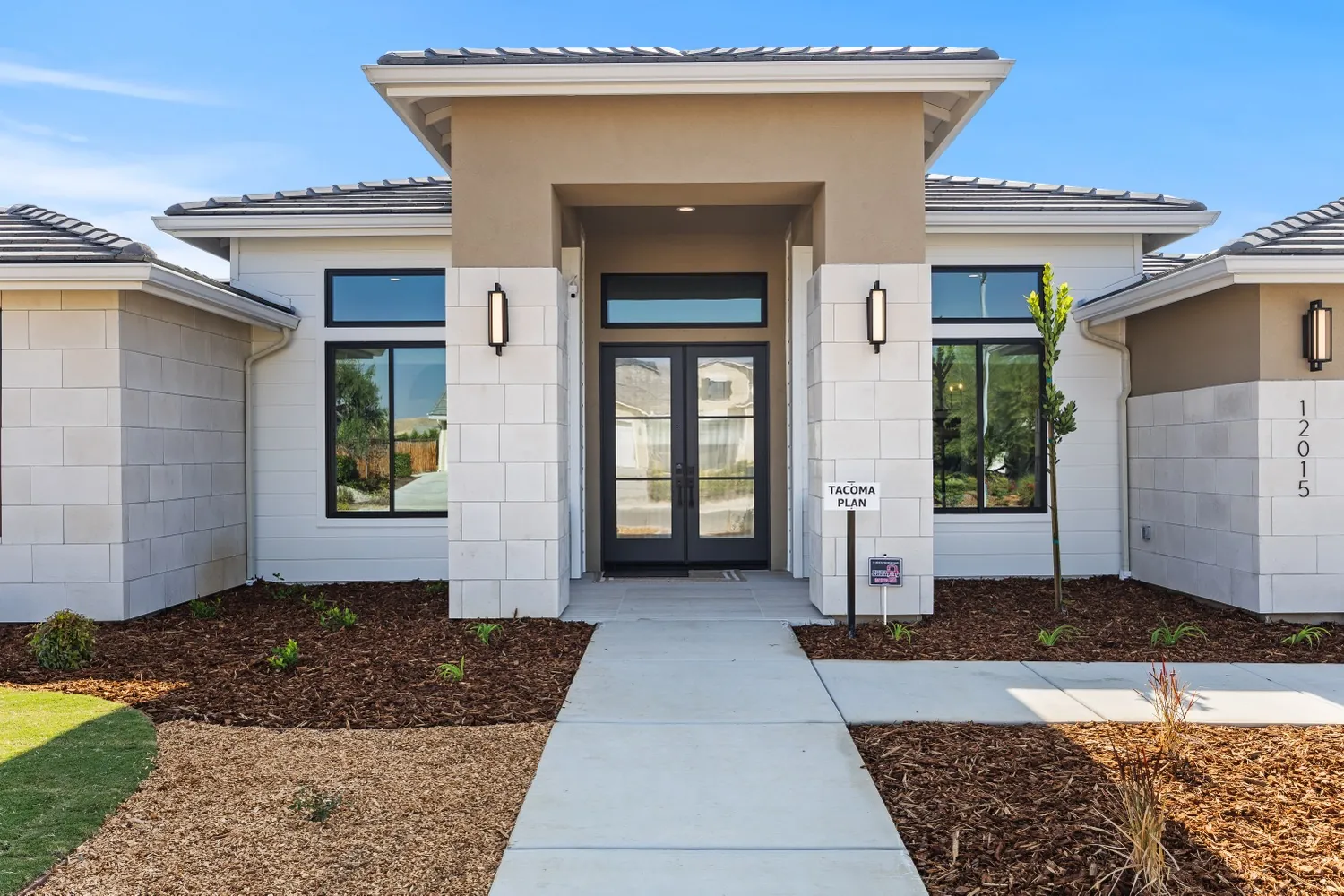 Front entry of a Tacoma model home with glass double doors between stone-look columns