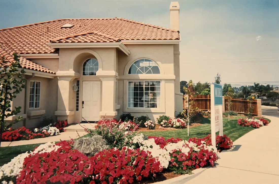 An early S&S home with a clay tile roof and flower beds in front